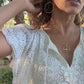 Video of black woman in garden in a white dress wearing Large gold hoop diamond earrings septagon shaped from the wandering jewel