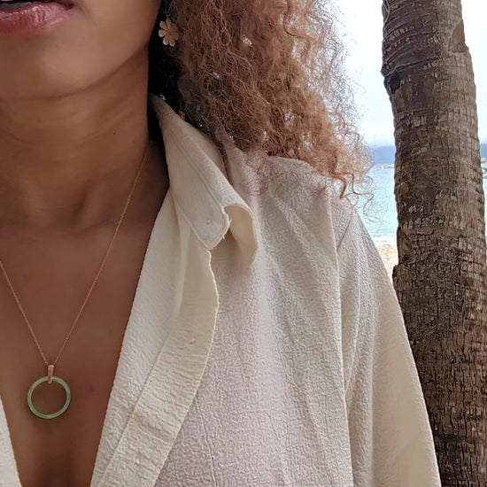 video of black woman in orange bikini and oversized white blouse on beach wearing the 18K Solid Rose Gold green jade ring on rose gold necklace from the wandering jewel