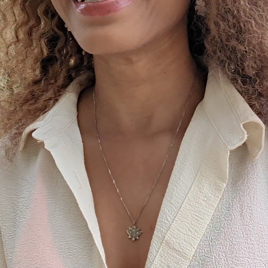 video of black woman in white blouse on a beach wearing the 7 diamond lotus necklace from the wandering jewel