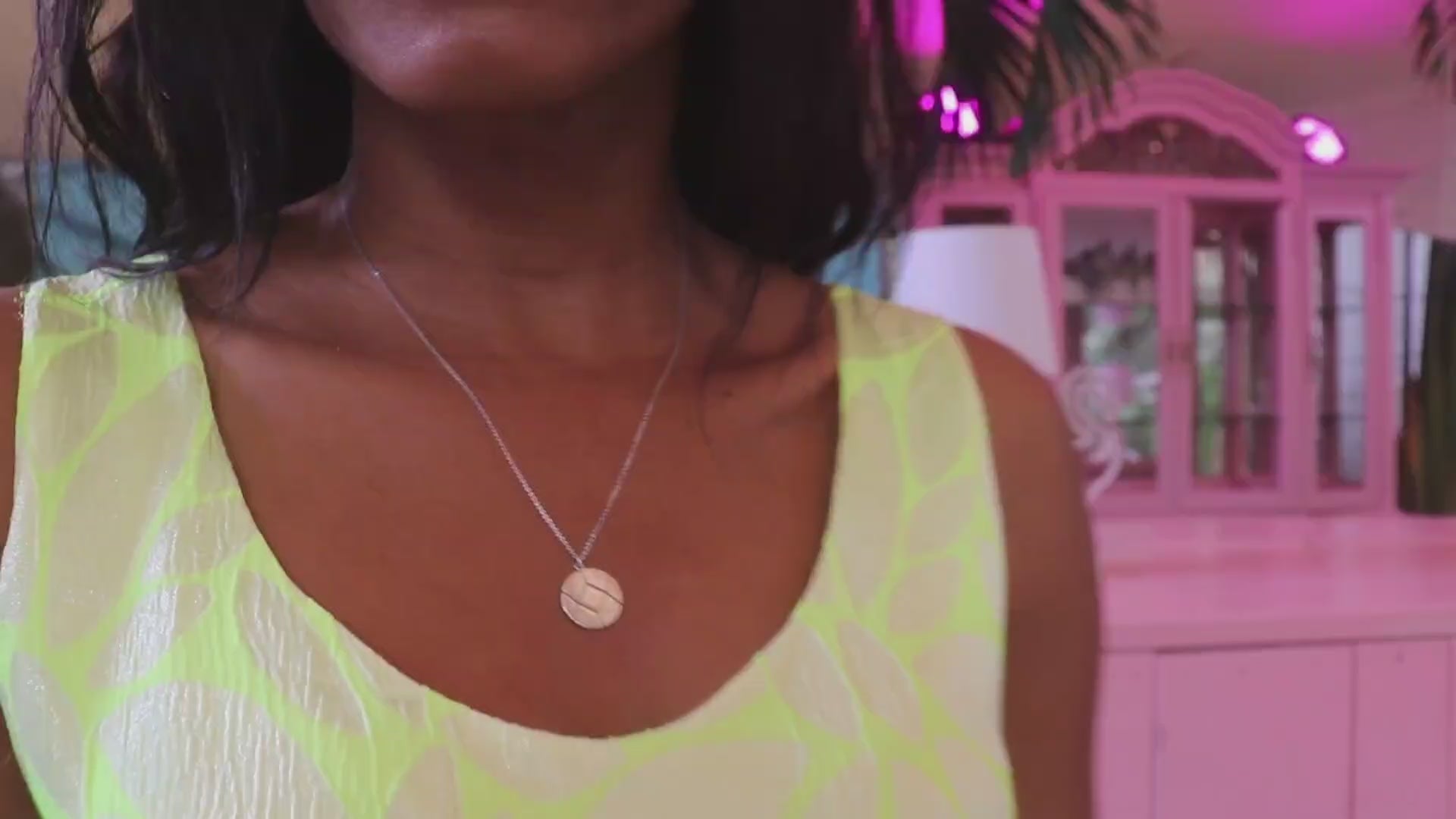 woman in neon yellow dress in pink room dancing and wearing the 7 diamond coin necklace from the wandering jewel