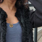 Woman in blue dress and fur necklace wearing the 7 diamond Semper Fi Coin Pendant necklace from the wandering jewel