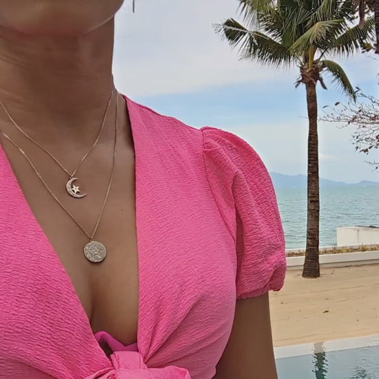 7 diamond moon & star coin and pendant on woman in pink outfit  on the beach from the wandering jewel