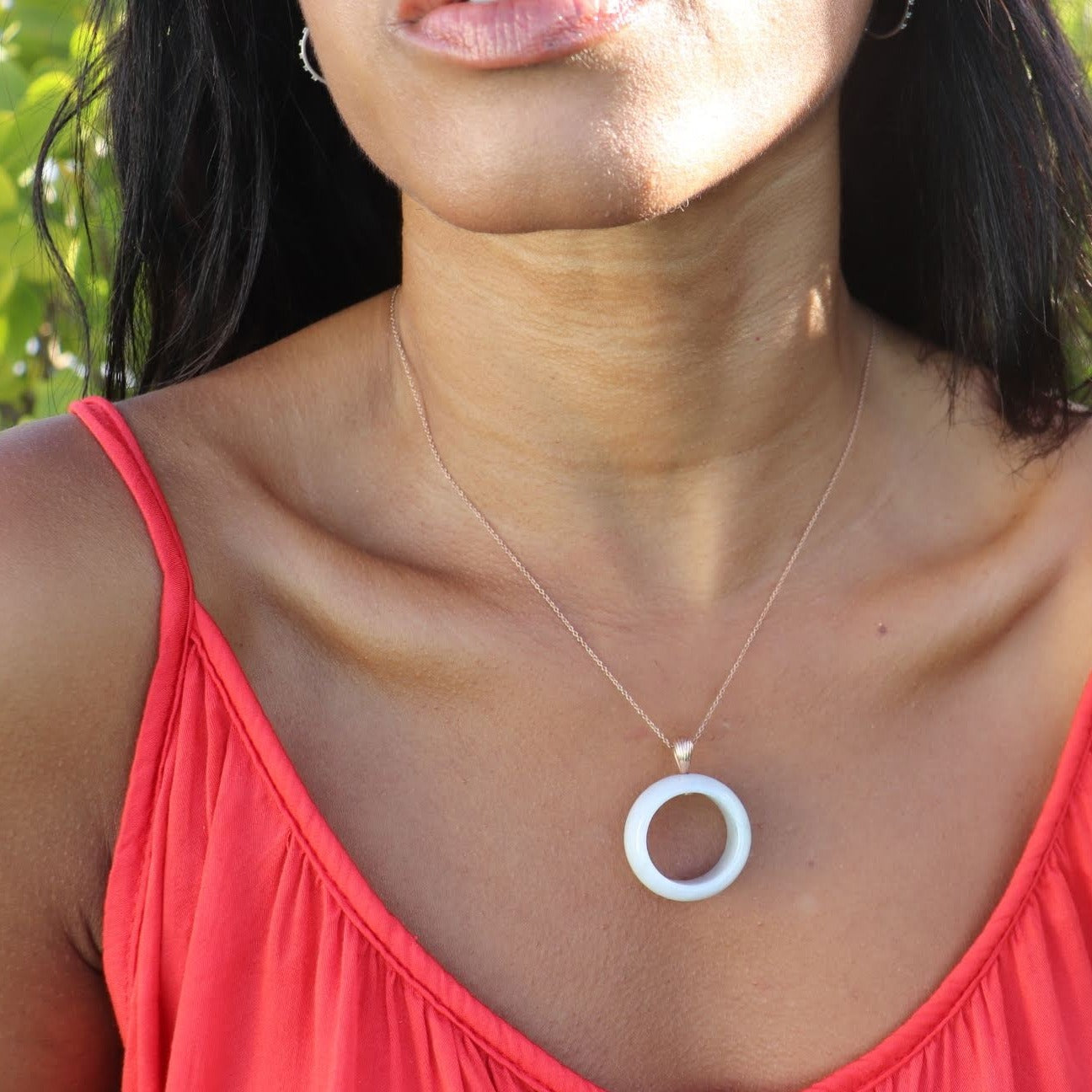 woman wearing orange top and wearing white jade ring necklace from the wandering jewel