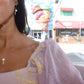 black woman in pink renaissance blouse standing in front of an ice cream parlor wearing an ice cream pearl pendant necklace 
