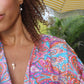 black woman with curly hair in a blue and purple paisley robe at pool wearing ice cream pearl pendant earrings and matching necklace from the wandering jewel