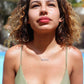 A beautiful woman at pool in green bikini looking up into the sky  wearing a nameplate necklace that says shekind