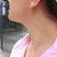 woman in pink top wearing dice earrings and matching necklace