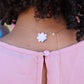 Back of neck view of woman in pink dress wearing Seven diamond logo plate on rose gold cloud with seven diamonds set evenly around the cloud from the wandering jewel
