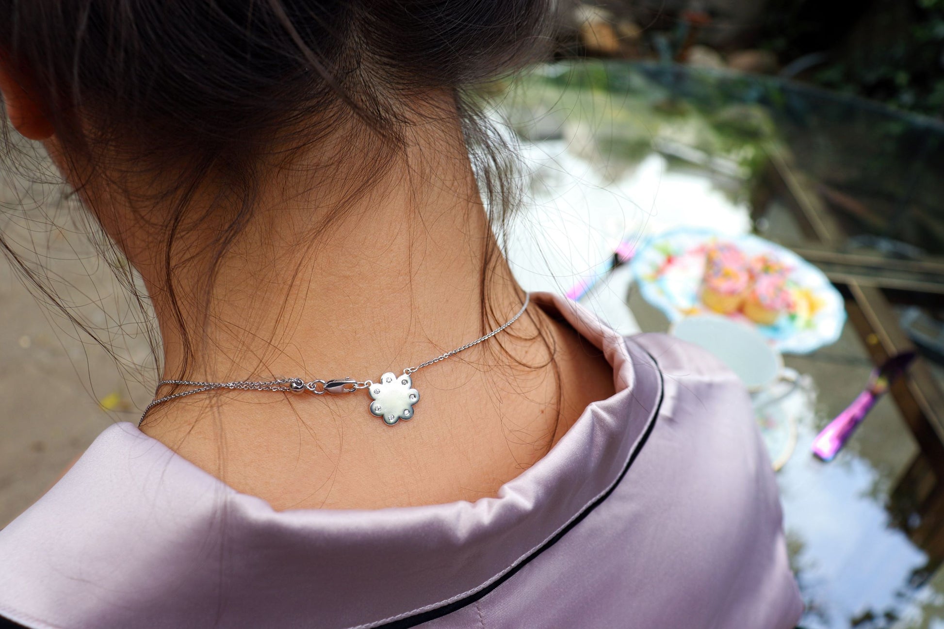 seven diamond logo plate shown on back of a  woman's neck from the wandering jewel