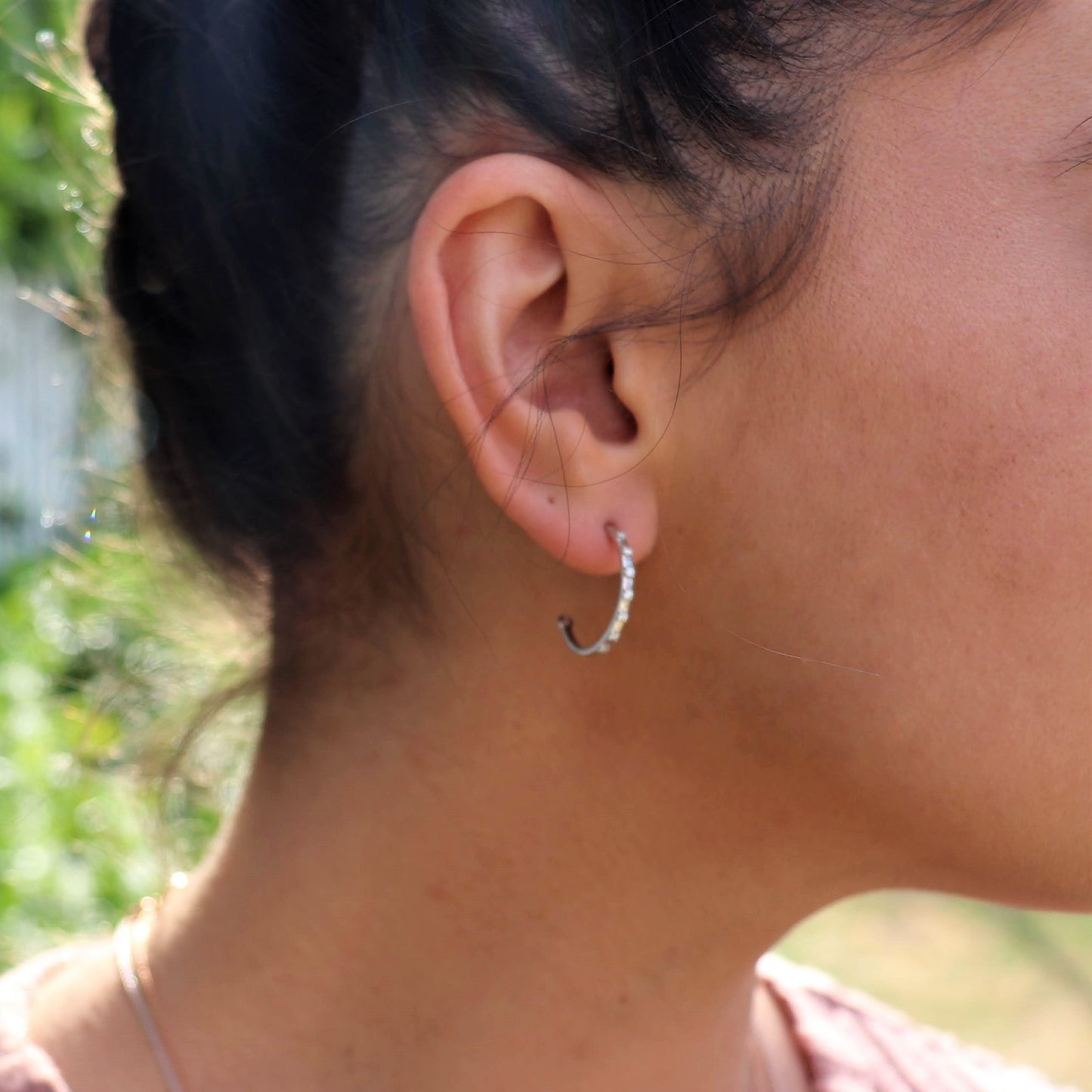 profile view of a woman wearing a silver diamonds earrings placed evenly in a medium sized hoop