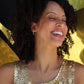 woman laughing and wearing a gold sequin dress and wearing diamond hoop earrings