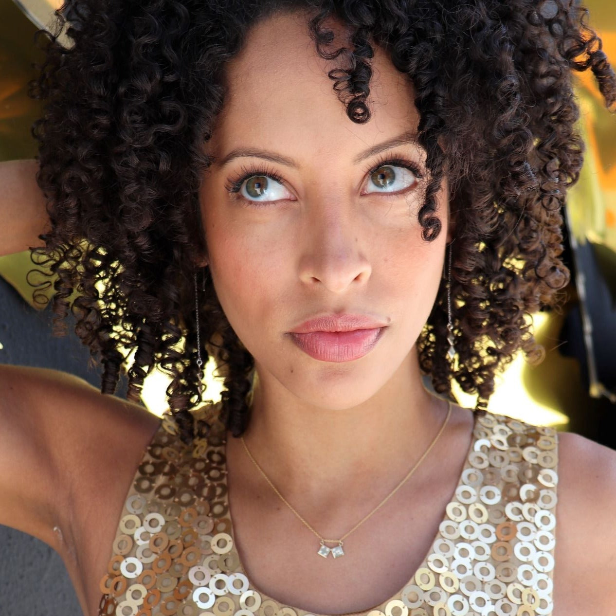 black woman with curly hair in gold sequin dress wearing dice earrings and matching dice necklace from the wandering jewel