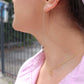 brunette woman in pink top looking to her right side wearing dice earrings and matching dice pendant