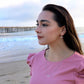 woman on beach in pink dress wearing diamond bar earrings and matching necklace from the wandering jewel