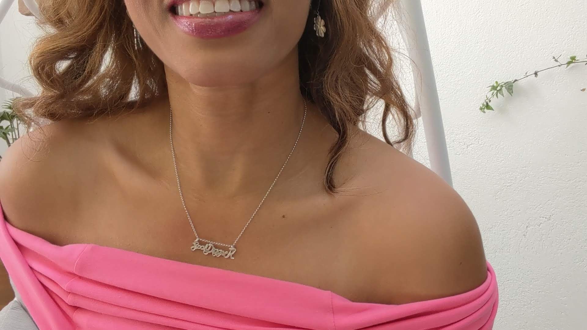 smiling black woman in pink dress wearing goaldigger necklace