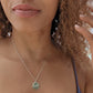 woman in purple swimsuit on beach with fishing boat in the background wearing Jehovah coin pendant  from the wandering jewel