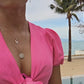 woman wearing pink outfit on beach and modeling the 7 diamond moonstar coin and pendant from the wandering jewel
