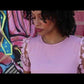 video of black woman with curly hair and a pink dress wearing two 7 diamond cross necklaces from the wandering jewel