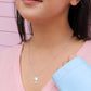 brunette woman wearing a pink t shirt and blue jean jacket  and a mini palm tree necklace