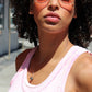 black woman with curly hair in pink tank top and pin sunglasses on sunset blvd wearing black pearl pendant from the wandering jewel