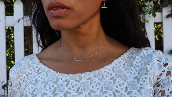 woman white dress in front of a picket fence wearing the 7 diamond horizon earrings from the wandering jewel