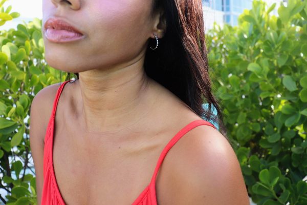 black woman sitting in garden in bright orange dress and wearing the 7 diamond cocktail earrings from the wandering jewel