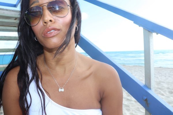 woman on beach sitting on lifeguard steps wearing a necklace from the wandering jewel