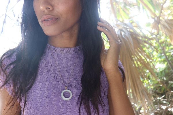 woman in purple dress looking to the right with her hand in her hair wearing white jade ring necklace from the wandering jewel