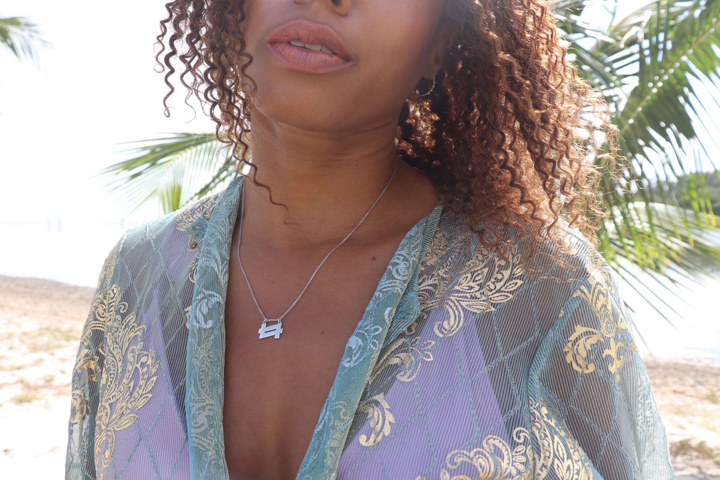 woman on beach in aqua robe wearing the double 7 necklace from the wandering jewel