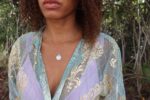 woman in a purple bikini and a matching aqua robe wearing the yahweh coin necklace fro the wandering jewel