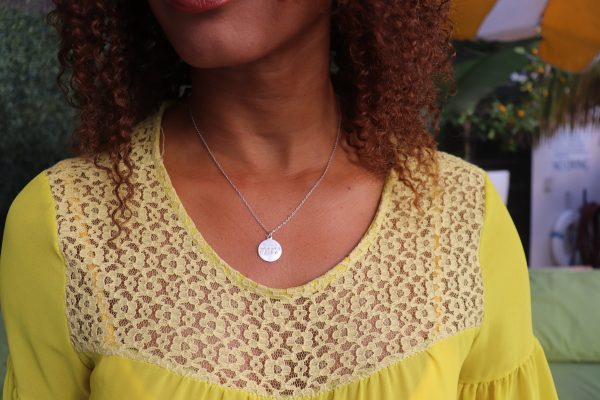 womani in yellow dress by the pool wearing the yahweh coin necklace from The Wandering Jewel