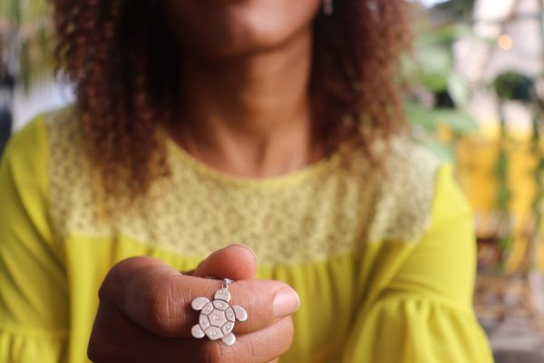 woman in yellow dress holding the 7 diamond turtle necklace from the wandering jewel