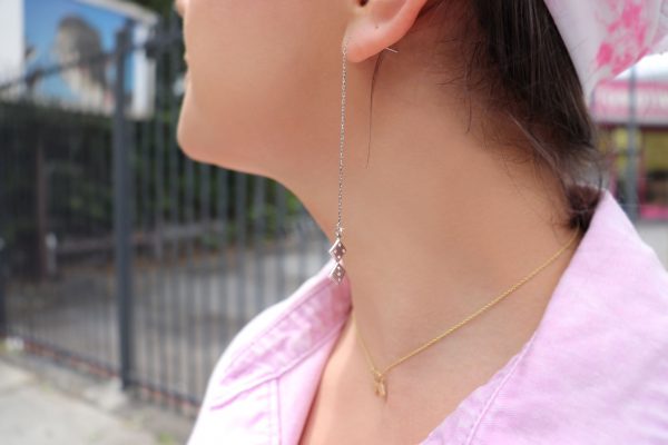 woman in pink top wearing dice earrings and matching necklace from the wandering jewel