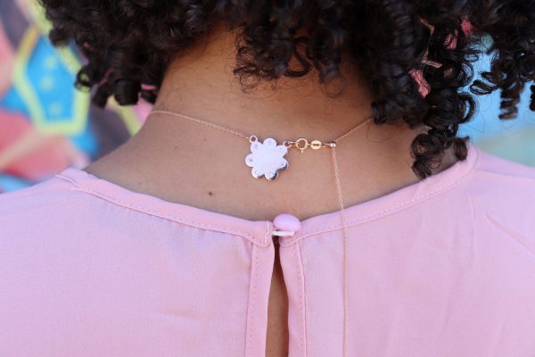 Rear view of woman with curly hair wearing Seven diamond logo plendant on rose gold cloud with seven diamonds set evenly around the cloud from the wandering jewel