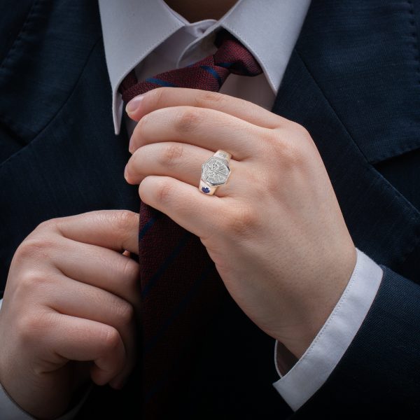 white man in suit fixing his tie wearing 925 Sterling silver cross septagon ring by the wandering jewel