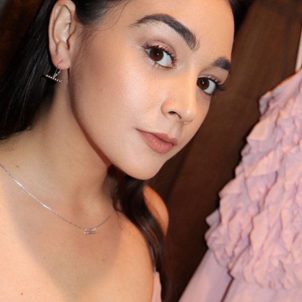 woman looking into camera in pink dress and wearing diamond bar earrings and matching necklace from the wandering jewel