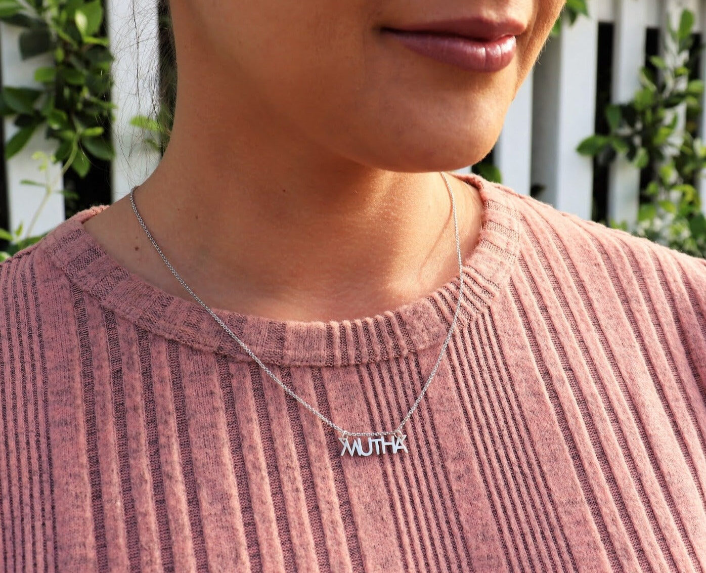 woman in pink shirt wearing mutha necklace