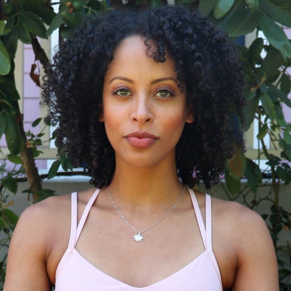 woman in purple sports bra looking directly into camera and wearing diamond lotus necklace from the wandering jewel