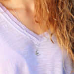 blonde Woman wearing a purple shirt and a diamond  moon and star pendant from the wandering jewel