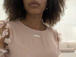 black woman in a pink dress wearing the SHEKIND necklace from the wandering jewel