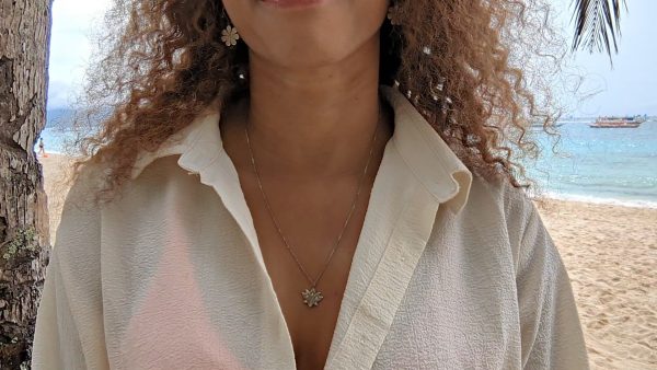 vwoman in white blouse on a beach wearing the 7 diamond lotus necklace from the wandering jewel