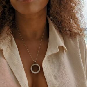 woman in white blouse on the beach wearing a jade necklace from the wandering jewel