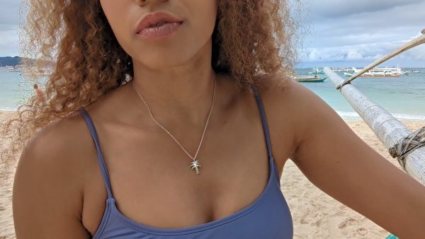 woman on beach in purple bikini wearing a silver palm tree necklace from the wandering jewel