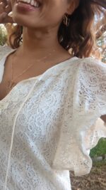 black woman in white dress outside wearing the 7 diamond butterfly earrings and necklace from the wandering jewel