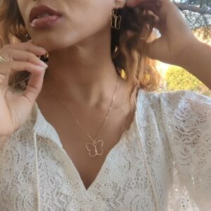 black woman in white dress in garden wearing the 7 diamond butterfly earrings and necklace from the wandering jewel