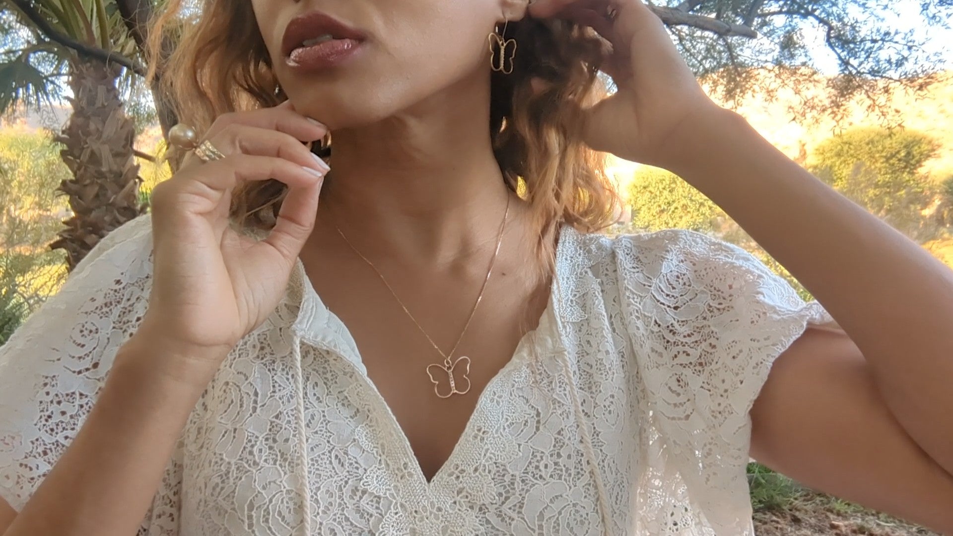 black woman in white dress in garden wearing the 7 diamond butterfly earrings and necklace from the wandering jewel