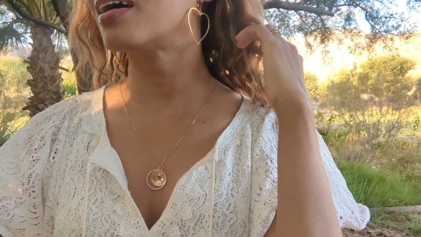 woman in white dress in garden wearing the large gold hoop heart shaped earrings from the wandering jewel