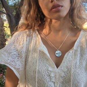 black woman in white dress in garden desert wearing the Jehovah cutout coin from the wandering jewel