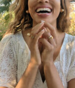 woman in white dress laughing in a garden and wearing multiple 7 diamond disengagement rings from the wandering jewel