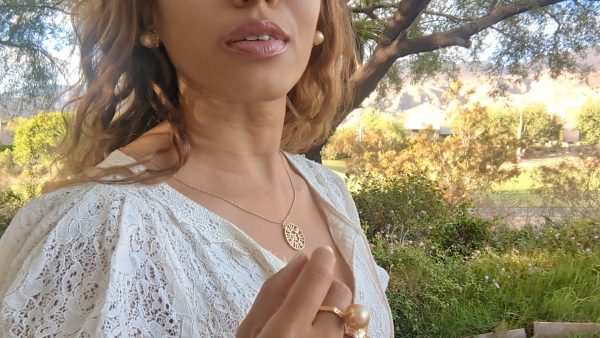 black woman smiling in garden wearing white dress and smiling while wearing the Large oversized South sea pearl diamond ring from the wandering jewel